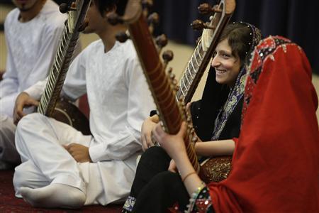 A girl smiles after playing the sitar during a performance by members of the Young Afghan Traditional Ensemble at the State Department in Washington